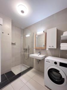 y baño con lavadora y ducha. en Modern apartment w/ cozy balcony near city center, en Viena