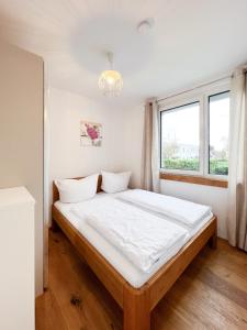 Schlafzimmer mit einem Bett mit weißer Bettwäsche und einem Fenster in der Unterkunft Modern apartment w/ cozy balcony near city center in Wien