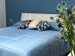 ein blaues Bett mit Kissen und eine blaue Wand in der Unterkunft Amalphia Home in Salerno