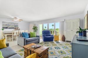 un soggiorno con divano, sedie e tavolo di Beach Oasis - Beautifully Remodeled Beachside Condo at Holiday Villas II with Heated Pool! a Clearwater Beach