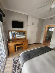 um quarto com uma cama e uma televisão na parede em Rosewood Guest Cottage em Vryheid