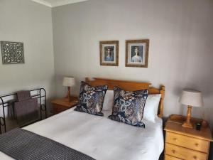 um quarto com uma cama e duas fotografias na parede em Rosewood Guest Cottage em Vryheid