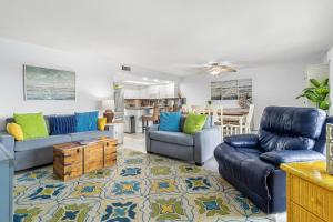 sala de estar con sofás azules y cocina en Beach Oasis - Beautifully Remodeled Beachside Condo at Holiday Villas II with Heated Pool!, en Clearwater Beach