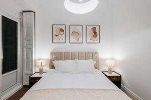 a white bedroom with a large bed with two lamps at Stunning Apartment near Gran Via Metro in Madrid
