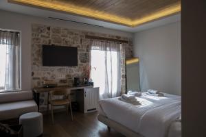 a bedroom with a bed and a desk and a television at Μikri Arktos Boutique Hotel in Dhimitsana
