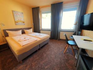 ein Hotelzimmer mit einem Bett, einem Schreibtisch und einem TV in der Unterkunft Hotel-Pension Grüne Linde in Delitzsch