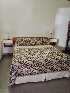 a bedroom with a bed with a black and white comforter at Alojamiento Alem in General Alvear