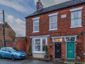 a blue car parked in front of a brick house at Pass the Keys Charming Victorian Hidden Gem in Market Drayton
