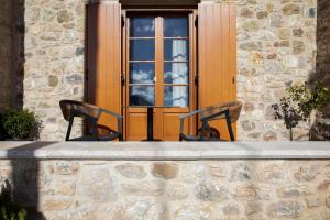 two chairs in front of a building with a window at Μikri Arktos Boutique Hotel in Dhimitsana