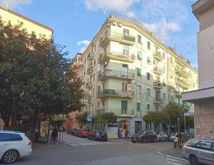 ein hohes Gebäude in einer Stadtstraße mit geparkten Autos in der Unterkunft Amalphia Home in Salerno