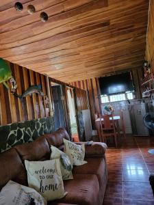 una sala de estar con sofá marrón y techos de madera. en Hospedaje las brisas, en Puerto Jiménez