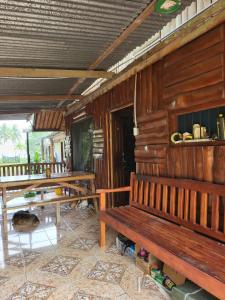 una cabaña de madera con bancos y mesas. en Hospedaje las brisas, en Puerto Jiménez