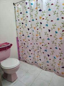 baño con aseo y cortina de ducha con mariposas en Hospedaje las brisas, en Puerto Jiménez