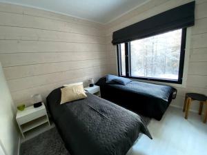 two beds in a room with a window at Villa Tykkylä Ruka in Kuusamo