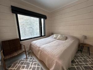 a bedroom with a bed and a window and a chair at Villa Tykkylä Ruka in Kuusamo