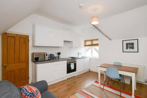 a kitchen with white cabinets and a table in a room at The Dagmar Grove Apartments in Nottingham