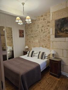 ein Schlafzimmer mit einem großen Bett und einer Steinmauer in der Unterkunft La Maison Colline in Saint-Émilion