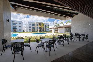 a patio with tables and chairs and a pool at Apartamento vista a piscina, gym y cerca de playa in Punta Cana