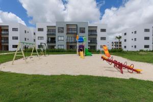 un parque infantil frente a un gran edificio en Apartamento vista a piscina, gym y cerca de playa en Punta Cana