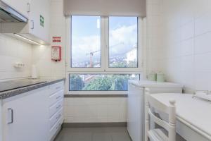 een witte badkamer met een wastafel en een raam bij Blue Sky in Funchal