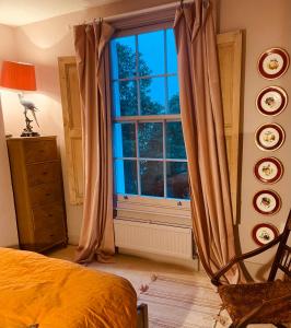 una camera da letto con una grande finestra e un letto di Beautiful London Victorian house, sleeps 12 a Londra