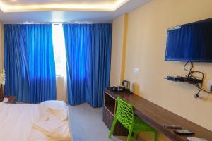 Un dormitorio con cortinas azules y un escritorio y una cama. en Arlinjai Paradise, en Kanyakumari 8 fotos más