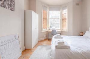 um quarto com uma cama branca e toalhas em Stylish 2 Bed Garden Flat in Zone 1 Central London em Londres