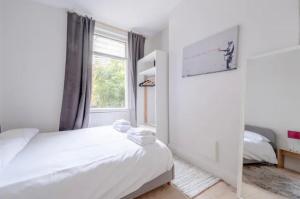 a white bedroom with a bed and a window at Stylish 2 Bed Garden Flat in Zone 1 Central London in London