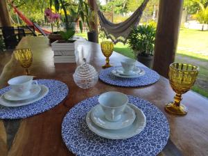 une table en bois avec des assiettes, des tasses et des verres bleus et blancs dans l'établissement Casa de ferias paraíso, à Santa Cruz Cabrália