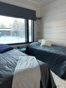 a bedroom with two beds and a large window at Villa Tykkylä Ruka in Kuusamo