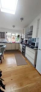 a kitchen with white cabinets and a wooden floor at Comfortable artistic house welcomes you! in Oxford