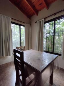 una mesa de madera en una habitación con ventanas en Aldea del Río en Santa Rosa de Calamuchita