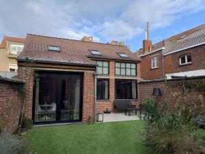 a large brick house with a patio in the yard at Gîte de Lombard 2 in Ieper