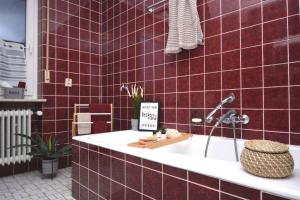 a red tiled bathroom with a tub with a sign on it at KU01-RI Apartment in Kulmbach EG in Kulmbach