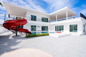 a large white house with a red slide at Holly house poolvilla in Ban Huai Yai