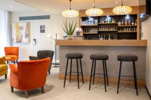 un bar dans un restaurant avec des chaises et des ools orange dans l'établissement Best Western Auray le Loch, à Auray