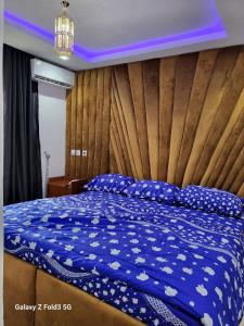 Schlafzimmer mit einem blauen Bett und einem Kopfteil aus Holz in der Unterkunft O'ffidaus J Luxury Hotel And Suites Int Ltd in Benin City