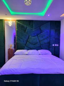 ein Schlafzimmer mit einem großen Bett mit grüner Beleuchtung in der Unterkunft O'ffidaus J Luxury Hotel And Suites Int Ltd in Benin City