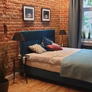 1 dormitorio con 1 cama azul y pared de ladrillo en BEST URBAN ROOMS parking free, en Lublin