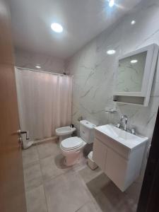 a white bathroom with a toilet and a sink at Complejo Las3B in General Roca