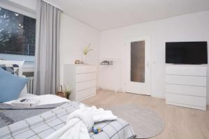 a white bedroom with a bed and a flat screen tv at KU-02RI Apartment in Kulmbach OG in Kulmbach