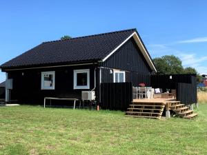 ein schwarzes Haus mit einem schwarzen Dach auf einem Feld in der Unterkunft Bo bekvämt i eget hus in Ekeby