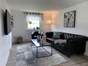 a living room with a black couch and a table at Bo bekvämt i eget hus in Ekeby