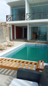 una piscina con 2 sillas y una casa en BUNGALOWS CASAMAR en Tumbes