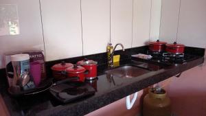 a kitchen counter with a sink and red pots and pans at Pousada Verde do Mato in Pirenópolis