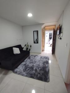 a living room with a black couch and a rug at BONITO APARTAMENTO CON GARAJE Piscina fuera del alojamiento a 500 mts in San Gil
