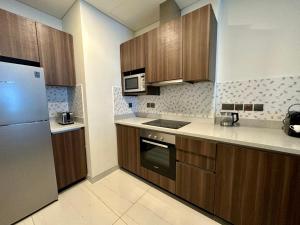 a kitchen with wooden cabinets and stainless steel appliances at Myhome Avani Palm View Dubai in Dubai