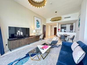 a living room with a blue couch and a tv at Myhome Avani Palm View Dubai in Dubai