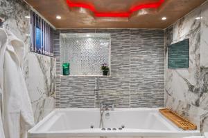 uma banheira branca numa casa de banho com azulejos em Hidden Gem Lt Properties Jaccuzi bath massage chair Superkingsize bed Parking available em Luton