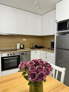 a vase of purple roses sitting on a table in a kitchen at NBG113 apartment in Belgrade